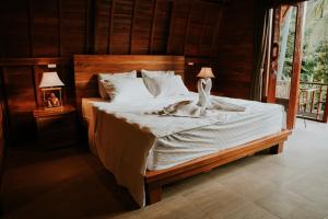 a bedroom with a bed with white sheets and two lamps at Kubu River View in Ambengan