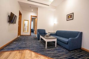 ein Wohnzimmer mit 2 blauen Stühlen und einem Tisch in der Unterkunft Platinum Al Khamseen in Ta'if