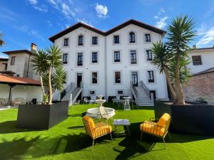 un gran edificio blanco con sillas, mesa y palmeras en Hotel Boutique Las Indianas en Nueva de Llanes