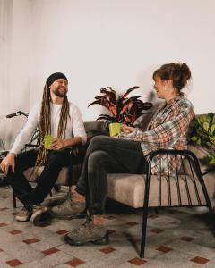 a man and a woman sitting on a couch with drinks at Wild Monkey Hostel in Cuenca