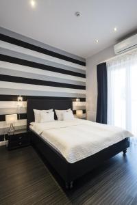 a bedroom with a large bed with a striped wall at Hotel Ankavi in Szeged