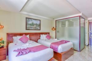 2 camas en una habitación de hotel con almohadas rosas en River Suites Hoi An, en Hoi An