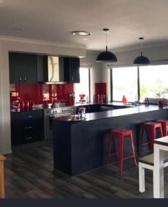 eine Küche mit roten Schränken und einer schwarzen Arbeitsplatte in der Unterkunft Gibbagunyah Manor Workers Accommodation Only in Muswellbrook