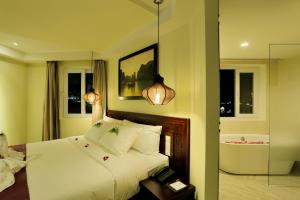 a bedroom with a white bed and two windows at River Suites Hoi An in Hoi An