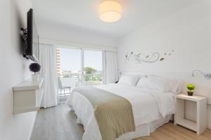 een witte slaapkamer met een wit bed en een raam bij 20 Hotel in Punta del Este