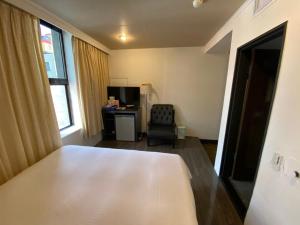 a bedroom with a bed and a desk and a chair at Queens Hotel in Taipei +24 photos