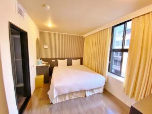 um quarto com uma cama e uma grande janela em Queens Hotel em Taipei