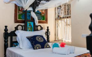 a bedroom with a bed with white sheets and pillows at Emerald Palm in Zanzibar City