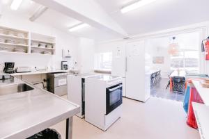 - une cuisine blanche avec comptoirs et appareils électroménagers blancs dans l'établissement Hlíd Hostel, à Mývatn