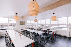 un comedor con mesas, sillas y ventanas en Hlíd Hostel, en Myvatn