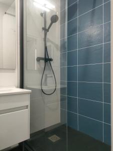 a bathroom with a shower with blue tiles at Super studio rez de jardin avec extérieur in Lozanne