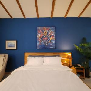 1 dormitorio azul con 1 cama y una pintura en la pared en JEJU Doldam B&B en Seogwipo