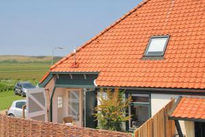 een huis met een oranje dak met een auto voor de deur bij de Dars in Callantsoog