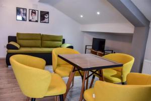 a room with yellow chairs and a table and a couch at Papi Apartments in Kruševo