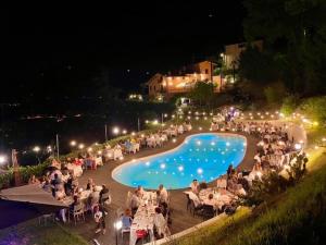 eine Gruppe von Menschen, die nachts am Pool sitzen in der Unterkunft Agriturismo Villa Paradiso Esotico in Città di Castello