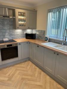 a kitchen with white cabinets and a wooden floor at The Poplars in Bridlington