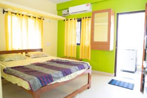 1 dormitorio con 1 cama y paredes verdes en Dhanashree Riverview Hotel, en Corgao 4 fotos más