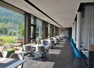 um restaurante com mesas, cadeiras e janelas em Boutique Hotel Moselgarten em Bullay