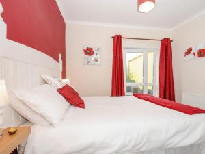 a bedroom with a white bed with red curtains at The Station Masters Lodge in Hayle