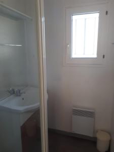 ein Bad mit einem Waschbecken und einem Fenster in der Unterkunft chalet Le Ticaco Soustons plage in Soustons