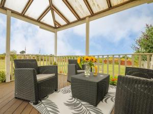 a patio with chairs and a table with a vase of flowers at The Station Masters Lodge in Hayle