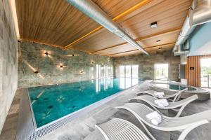 an indoor swimming pool with chairs around it at Panorama Golf Resort in Kácov