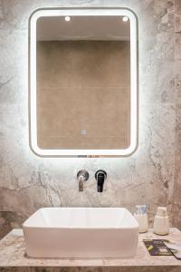 ein Waschbecken mit einem großen Spiegel darüber in der Unterkunft Quattro Luxury Apartments in Tríkala