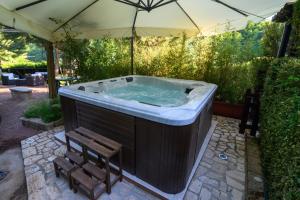 a hot tub in a backyard with a chair and an umbrella at Agriturismo le Fontane - Lago di Bolsena in Grotte di Castro