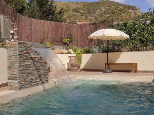una piscina con una fuente y una sombrilla en Apartamento rural NÍVALIS, en Nívar