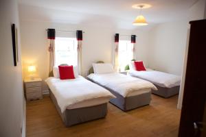 a room with three beds with white and red pillows at Paddy Mac's Self Catering Holiday Bar in Drumshanbo