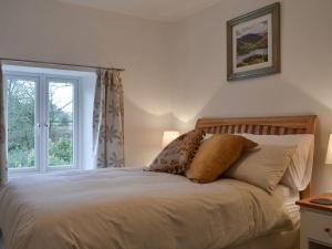 ein Bett mit Kissen und ein Fenster im Schlafzimmer in der Unterkunft Riverside Cottage in High Nibthwaite