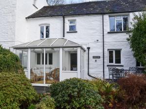 a white house with a screened in porch at Riverside Cottage in High Nibthwaite
