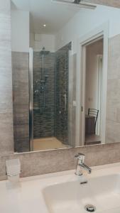 einen Badezimmerspiegel mit einem Waschbecken und einer Dusche in der Unterkunft Guesthouse Aschenez in Reggio di Calabria
