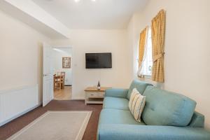 a living room with a blue couch and a tv at Cottage 8 Old Farmhouse braithwaite in Keswick