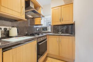 a kitchen with wooden cabinets and a sink at Cottage 8 Old Farmhouse braithwaite in Keswick