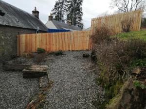 a backyard with a fence and a gravel yard at Smithy Cottage in Blairgowrie