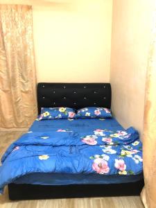 1 cama con edredón azul y almohadas en Ain Homestay, en Kuala Terengganu