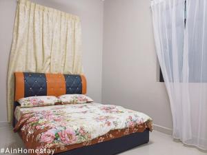 1 dormitorio con 1 cama con edredón de flores y ventana en Ain Homestay, en Kuala Terengganu