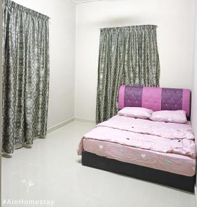 Cama rosa en habitación con cortinas en Ain Homestay, en Kuala Terengganu