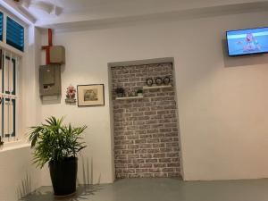 a room with a brick wall and a television on a wall at Homestay "Feel at Home" Near A Famosa & Jonker Street for 4-7 people in Melaka