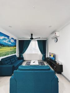 ein Wohnzimmer mit einem blauen Sofa und einem TV in der Unterkunft Hikaru Homestay Ladang Tanjung, Kuala Terengganu with POOL in Kuala Terengganu