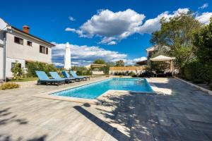 a swimming pool with blue lounge chairs next to a house at Apartman LuNi sa bazenom - Malinska, Sveti Anton in Sveti Anton
