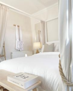 a white bedroom with two beds and a book on a table at Queens stay, Seaburn in Sunderland