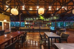 restauracja z drewnianymi stołami, krzesłami i światłami w obiekcie Borneo Sepilok Rainforest Resort w mieście Sepilok