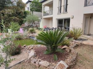 a garden with a small pond in front of a house at appartement coubillou in Lamalou-les-Bains