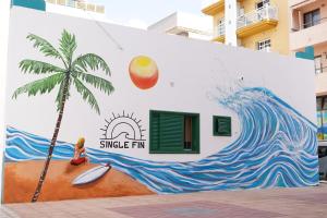 a mural of a palm tree on the side of a building at Single Fin Hostel in Arona