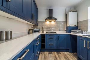 a blue kitchen with white counters and blue cabinets at Westfield 3 Bed Characterful and Modern House FREE PARKING and private garden in Mansfield