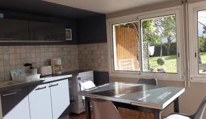 une cuisine avec des placards blancs, une table et une fenêtre dans l'établissement Apartment Les Claudalies, à Ploufragan