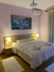 a bedroom with a large white bed with two lamps at Ballo Apartments in Gjirokastër