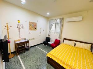 a bedroom with a yellow bed and a desk and chairs at Xingang Homestay in Xingang
